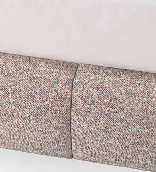 Double bed with short headboard, upholstered in multicolored fabric, primarily red and blue.