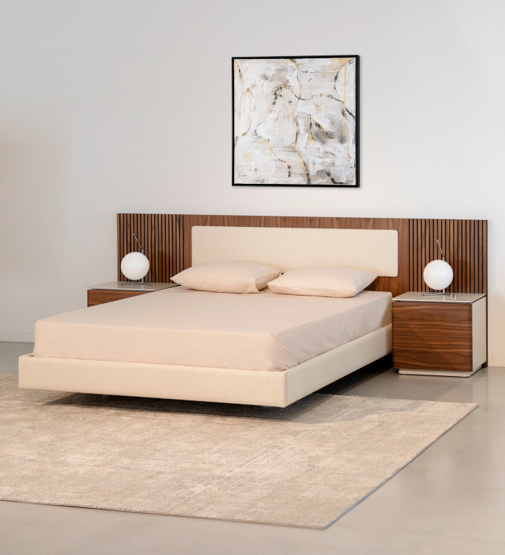 Cama doble con panel central del cabecero y base suspendida tapizados en tejido beige, laterales del cabecero con molduras de nogal natural.