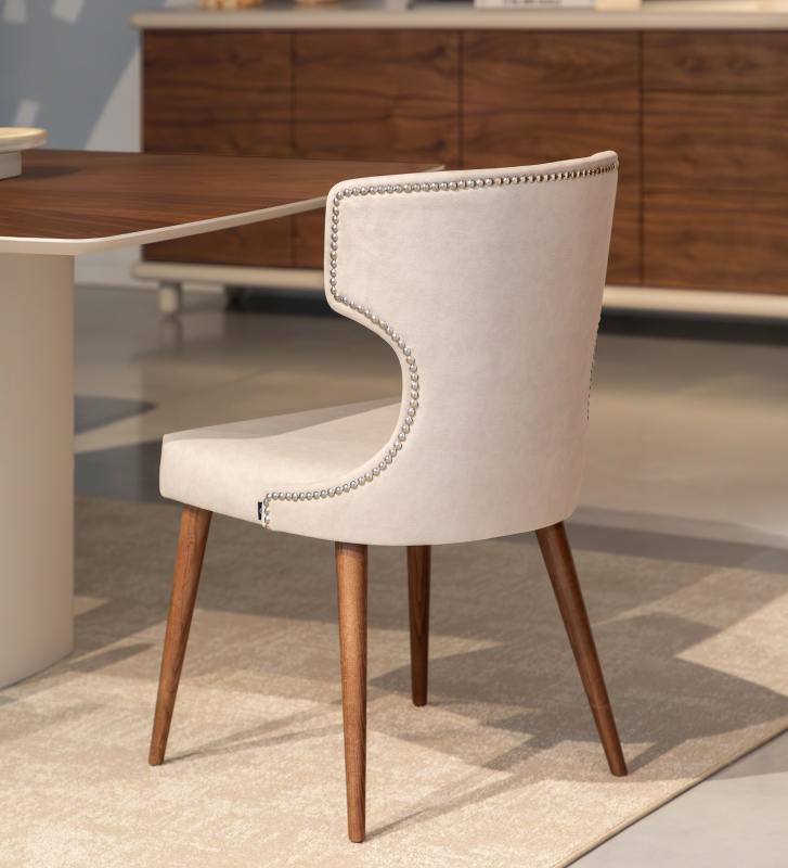 Upholstered chair in pearl fabric, with silver studs on the back and ash wood legs in walnut finish.