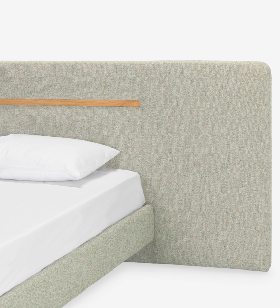 Double bed with upholstered headboard and floating base in green fabric, detail in natural oak.