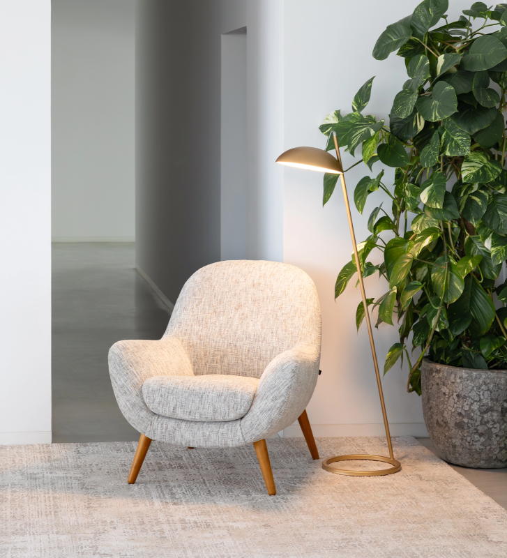 Fauteuil Oslo revêtu d’un tissu gris effet velours, avec des pieds en frêne couleur miel.