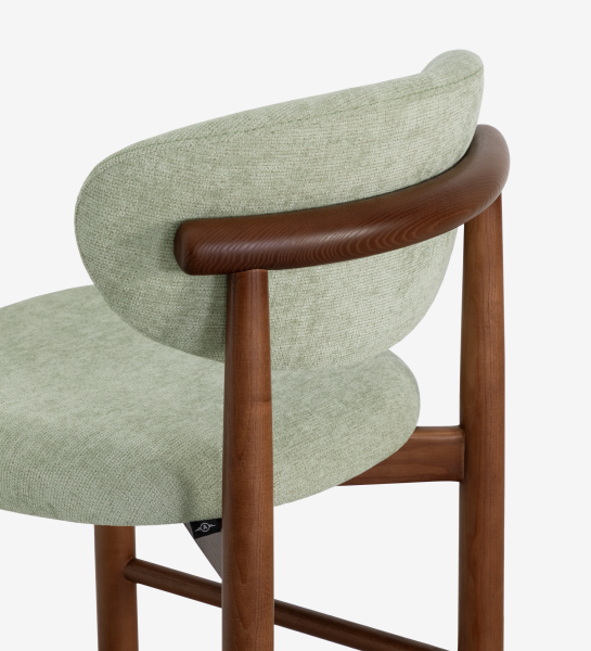 Taburete en madera de fresno color nogal, con asiento y respaldo tapizados en tela verde.