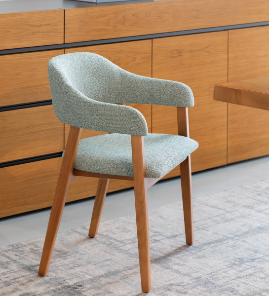 Chaise avec accoudoirs, en bois de frêne couleur miel, avec assise et dossier recouverts de tissu vert.