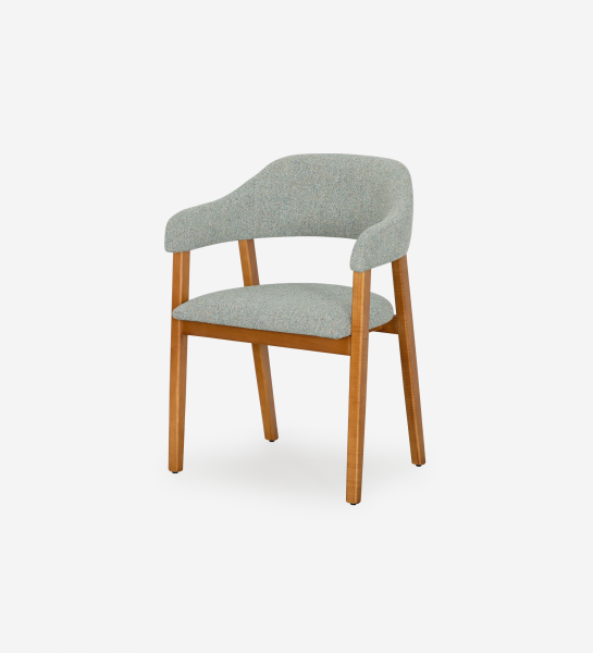 Chaise avec accoudoirs, en bois de frêne couleur miel, avec assise et dossier recouverts de tissu vert.