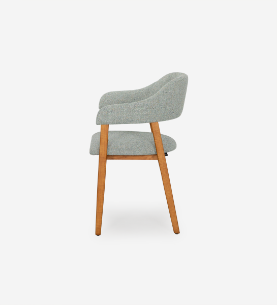 Chaise avec accoudoirs, en bois de frêne couleur miel, avec assise et dossier recouverts de tissu vert.