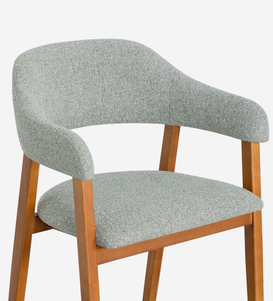 Chaise avec accoudoirs, en bois de frêne couleur miel, avec assise et dossier recouverts de tissu vert.