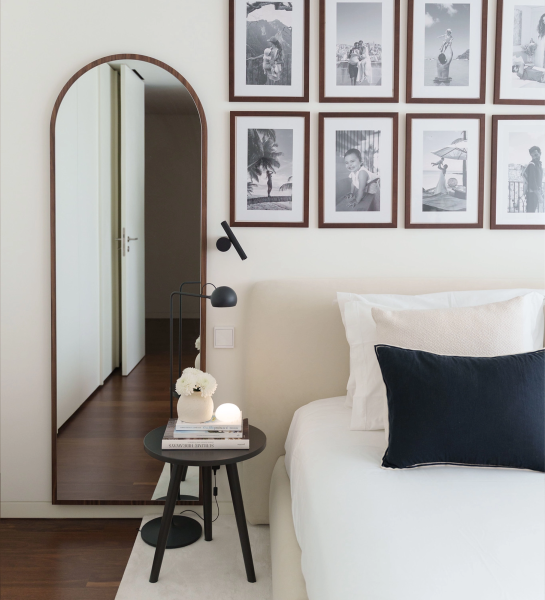 Miroir Haut Cannes en arc près d'un lit avec table de chevet et cadre photo mural