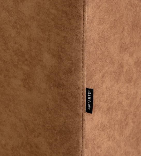 Close-up of tan suede-like upholstery seam and black fabric tag on Barcelona Sofa