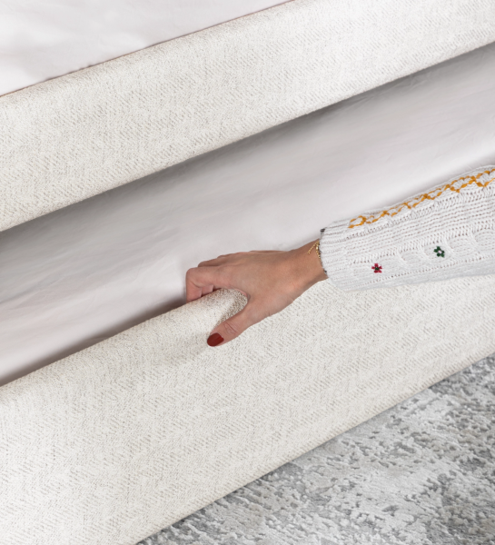 Lit de Divan avec structure et façade de tiroir rembourrées en tissu perle, avec lit dans le tiroir inférieur.