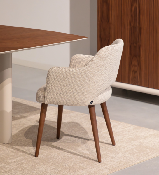 Cadeira com braços estofada a tecido de tons bege e pé em madeira cor nogueira.