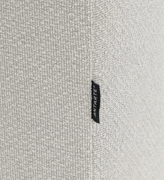 Primer plano del sofá Lagos en tejido beige claro con etiqueta negra 'ANTARTE'.