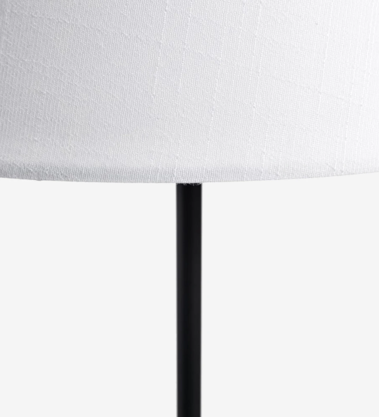 Lámpara de sobremesa con base de metal pintado de negro y pantalla de tela forrada en blanco.